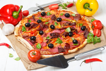 Pizza with vegetables and salami on wooden table