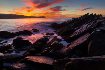 Sunset on ocean beach with rocks