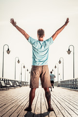Fototapeta na wymiar Man on pier with raised hands arms. Freedom.