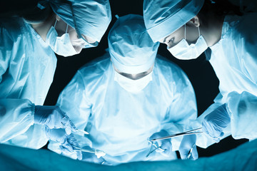 Medical team performing operation - obrazy, fototapety, plakaty