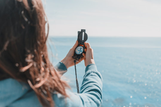 Traveler woman with a compass on coastline