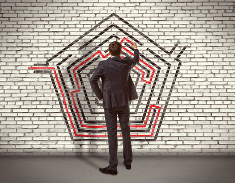 Businessman drawing labyrinth on wall