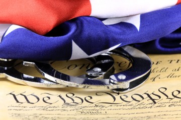 Handcuffs and American flag on US Constitution-Fourth Amendment