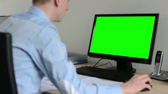 man works on desktop computer in the office - use mouse - green screen 