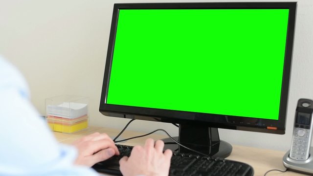 man works on desktop computer in the office - green screen - closeup