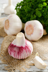 Garlic and a bunch of parsley on a white table