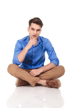 Handsome young fashion man sitting with his legs crossed.