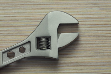 adjustable wrench closeup on wooden background