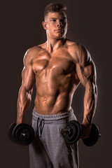 Fototapeta na wymiar muscular bodybuilder man posing with dumbbells