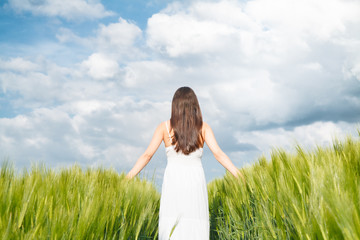Fototapeta na wymiar Young woman walking through wheat field
