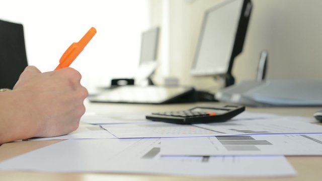 woman working in the office - writing on paper with highlighter - shot on paper