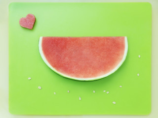 Slice of watermelon without seeds and heart of melon on green 
