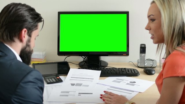woman and man talk about document in the office - desktop computer green screen