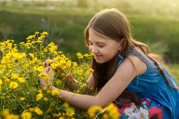 Fototapeta premium little girl smelling a yellow flower