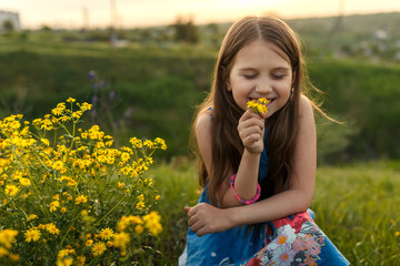 little girl smelling a yellow flower