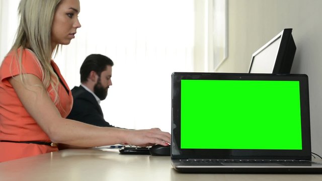 computer (laptop) - green screen - man and woman work on the computer in the office in the background