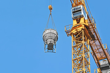 Fototapeta premium Crane lifting concrete mixer container against blue sky