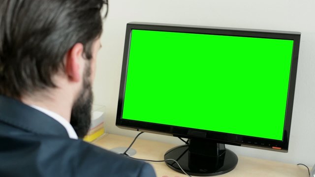 young handsome man with full-beard (hipster) works on desktop computer in the office - closeup