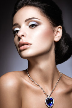 Beautiful brunette with a bright evening make-up with a necklace