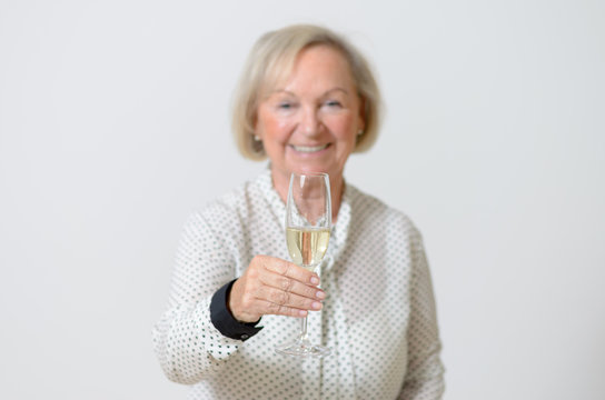 Attraktive Seniorin trinkt ein Glas Sekt