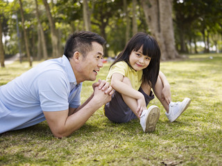 asian father and daughter having a conversation in park