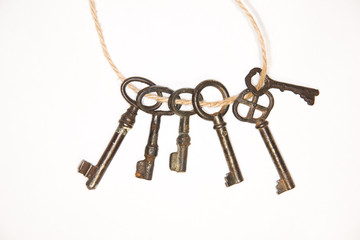 A lot vintage keys on a rope on white background