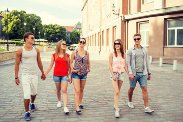 Fototapeta premium group of smiling friends walking in the city