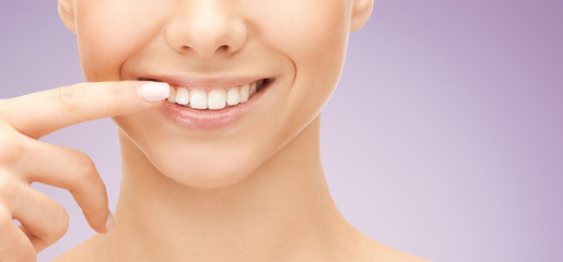 close up of smiling woman face pointing to teeth