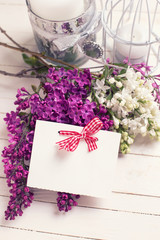 Fototapeta na wymiar Postcard with lilac flowers on wooden background.