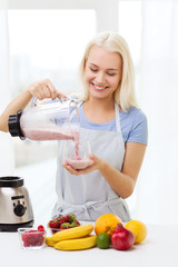 smiling woman with blender preparing shake at home