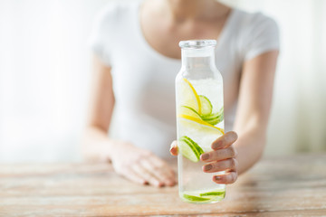 close up of woman with fruit water in glass bottle