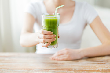 close up of woman hands with green juice