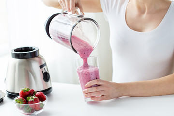 close up of woman with blender pouring milk shake