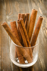 Cinnamon sticks in the glass on wooden background