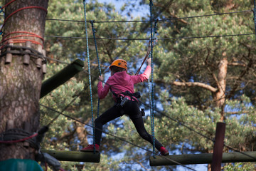 Girl climbing in adventure park , rope park  
