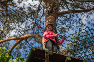 Girl climbing in adventure park , rope park  
