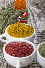 White ceramic cups with different kinds of spices on old wooden