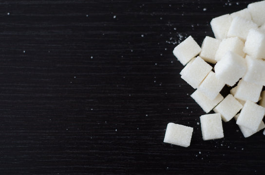 White sugar cubes piled in heap on the black desk