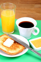 breakfast: cup of coffee, toasts, jam, butter and orange juice
