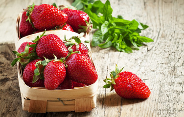 Fresh strawberries in a wicker basket on lerevyannom background,