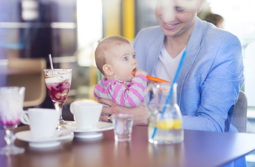 Young father with his cute baby daughter in cafe
