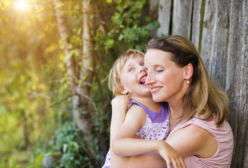 Happy mother with her little daughter at the wooden fence
