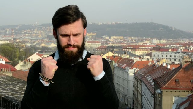 young handsome man with full-beard (hipster) is depressed - city in background
