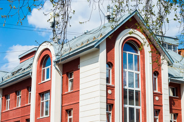 красивое современное здание из красного кирпича с белой отделкой на фоне голубого неба