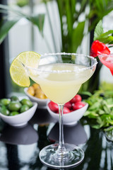 mix of the two bright cocktails: lime daiquiri and strawberry daiquiri on a table with creative decoration of salt on the edge of the glass with fresh mint and lime slices and berries.