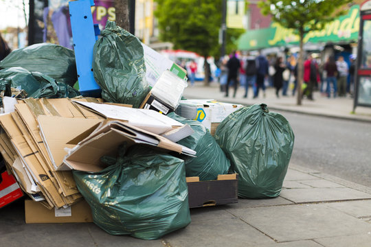 Litter and rubbish bags on the sidewalk of a busy street