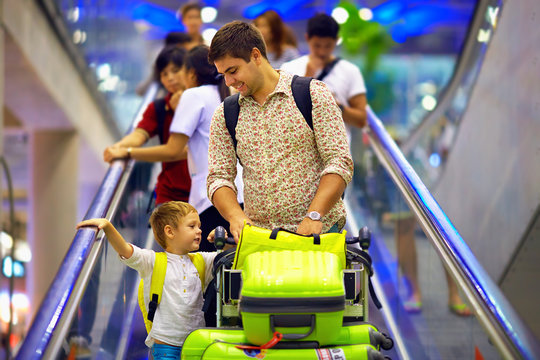 happy family with baggage on conveyor in airport