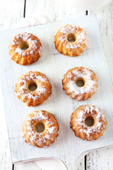 Bundt cakes on cutting board on white wooden background