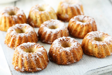 Bundt cakes on cutting board on white wooden background