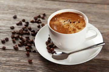 Cup of coffee with coffee beans on grey wooden background